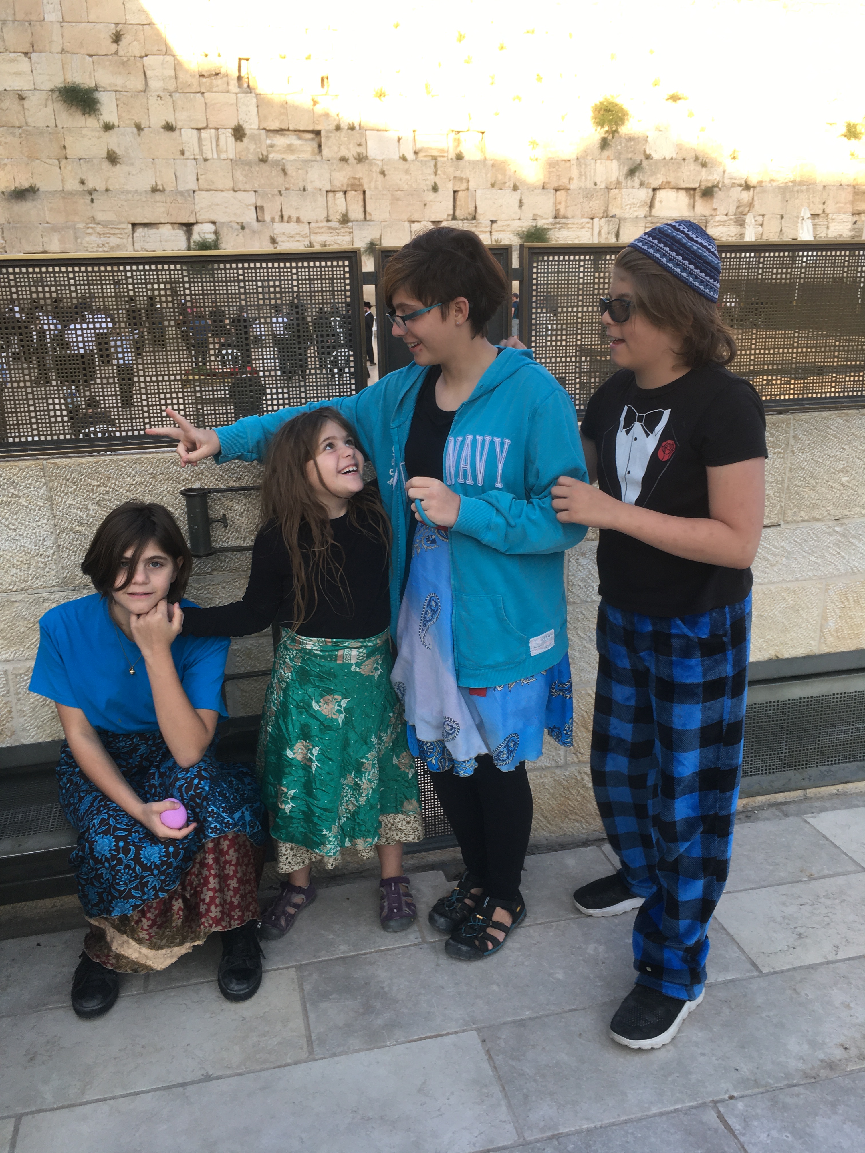 Four kids in front of the Western Wall. E and K are looking at each other and smiling.