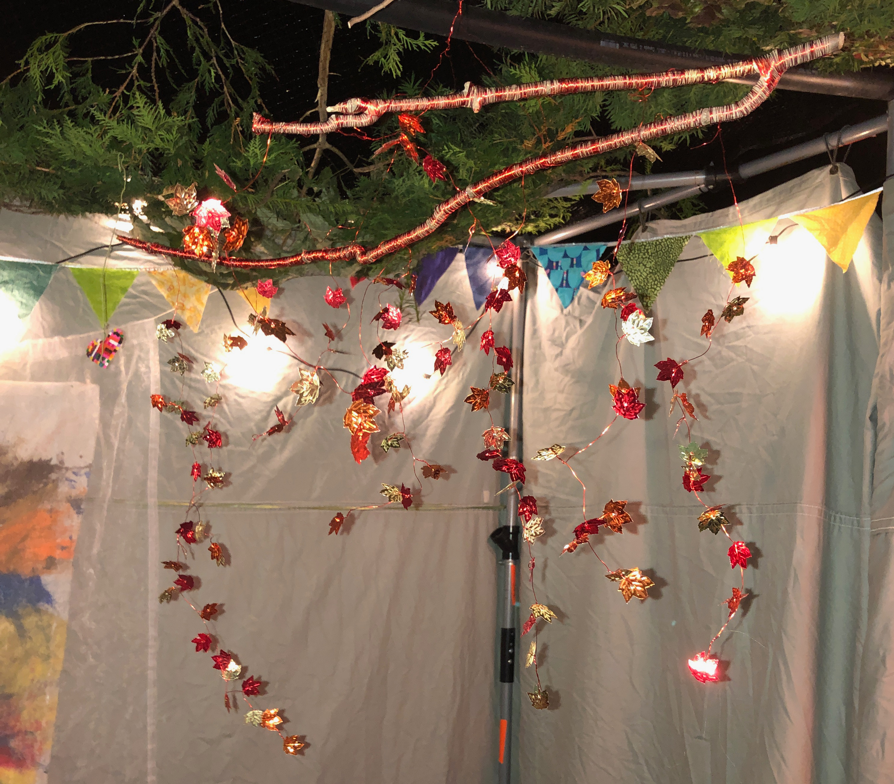 Decorative mobile made of a tree branch, with foil confetti shaped like maple leaves strung on wires that hang from the branches.
