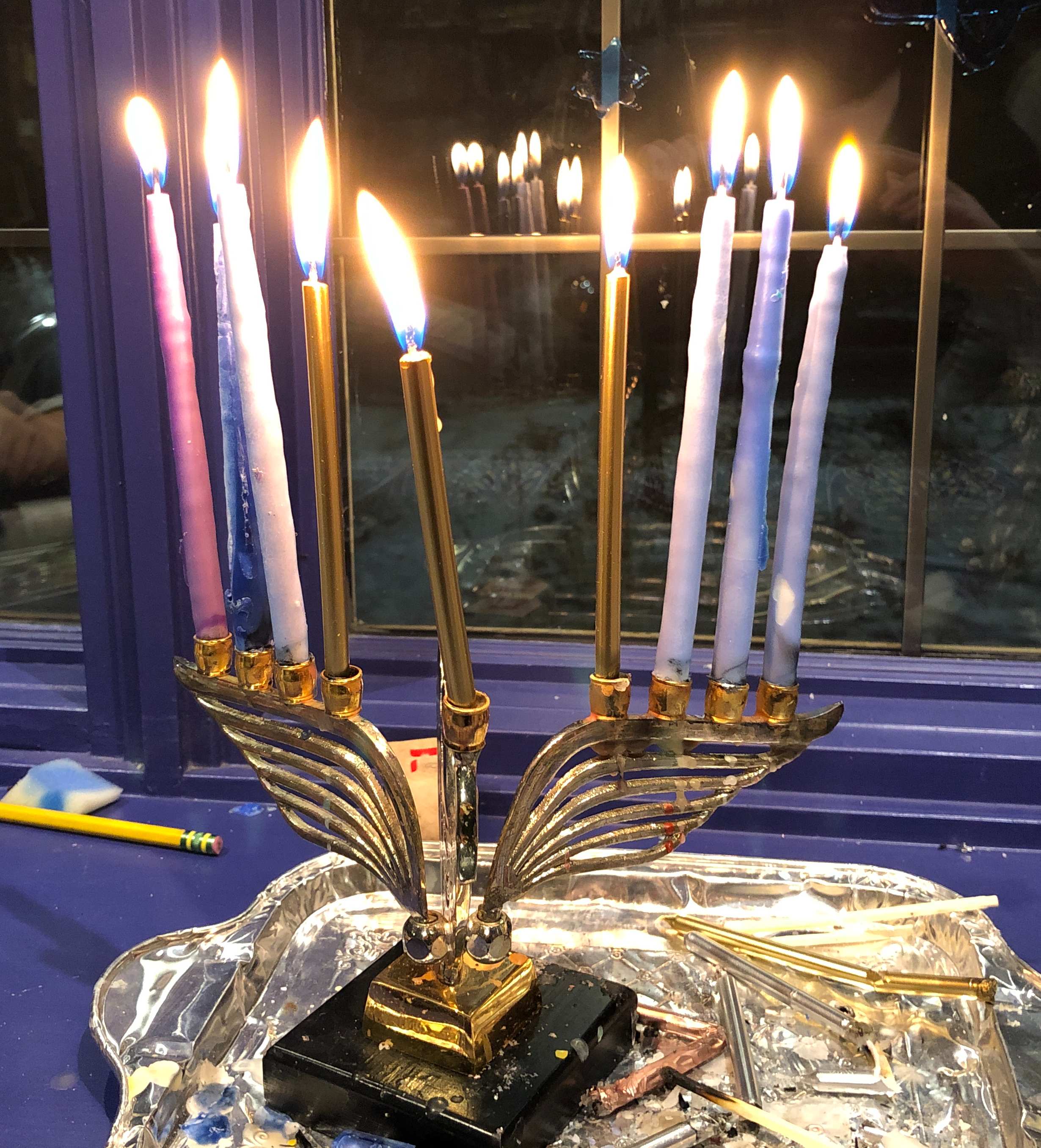 A dove-shaped hannukah menorah with all eight candles lit.