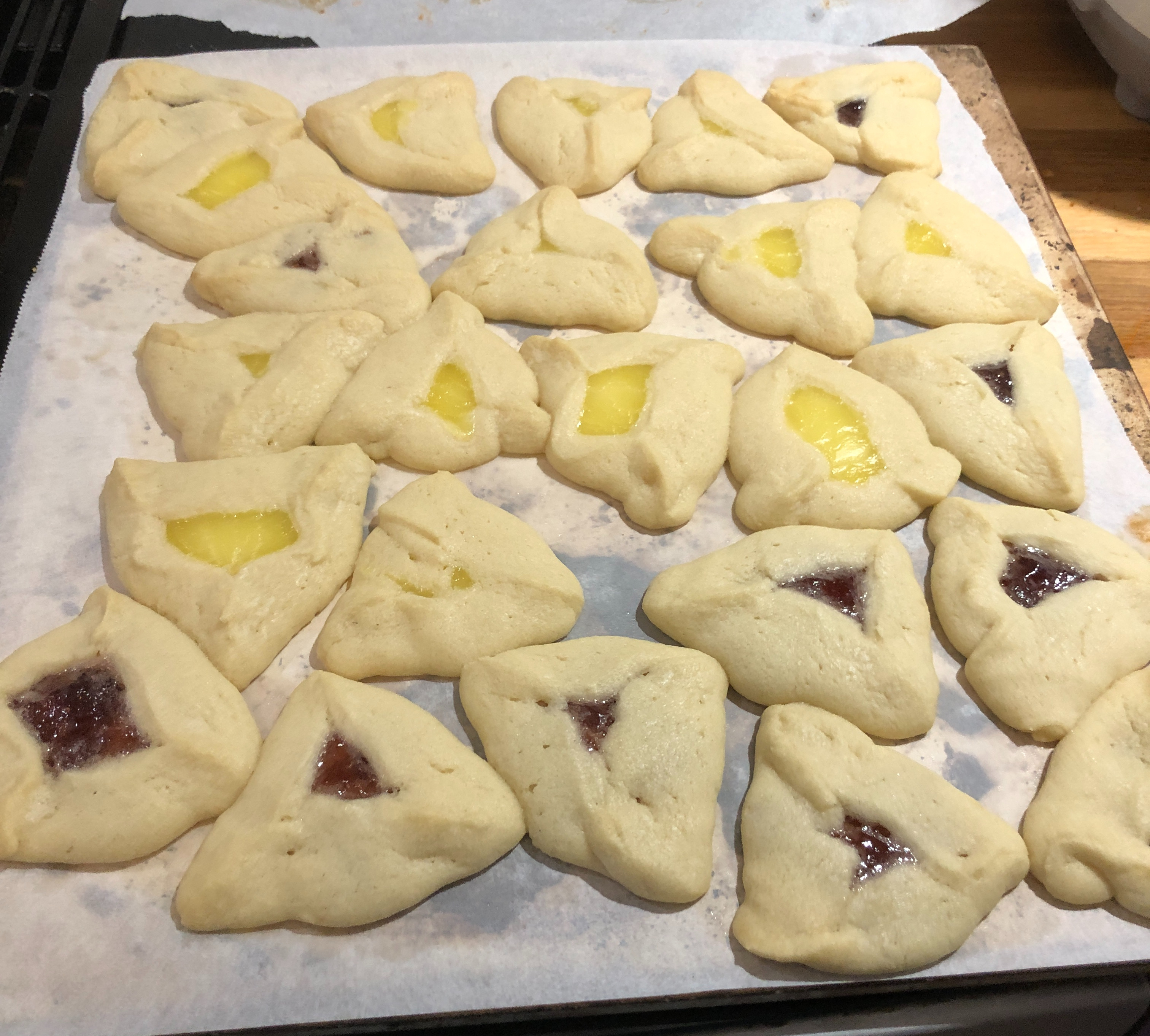 a tray of hamentaschen (triangular jam-filled cookies)