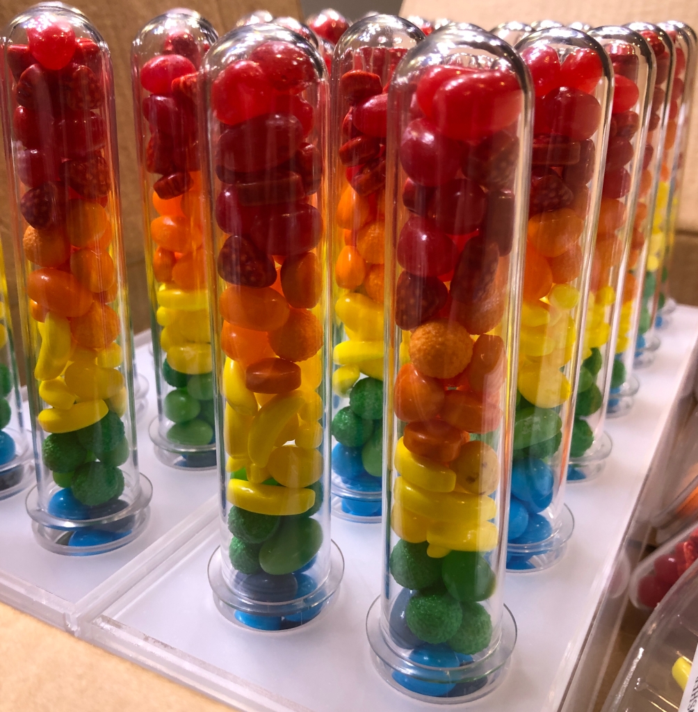 inverted test tubes filled with candy, in rainbow order.
